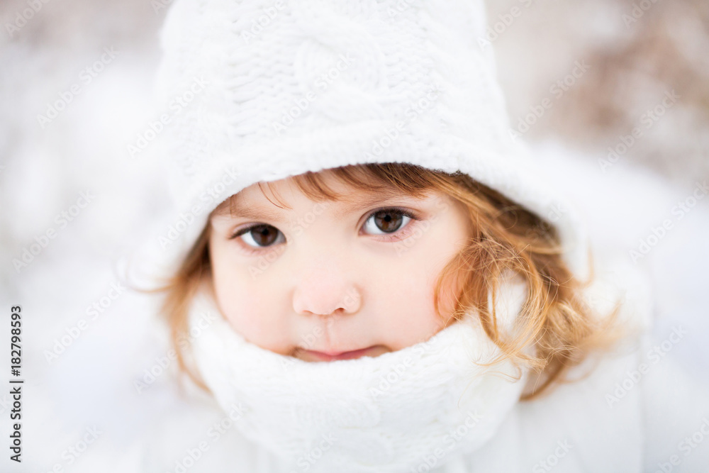 Little cute toddler girl outdoors on a sunny winter day.