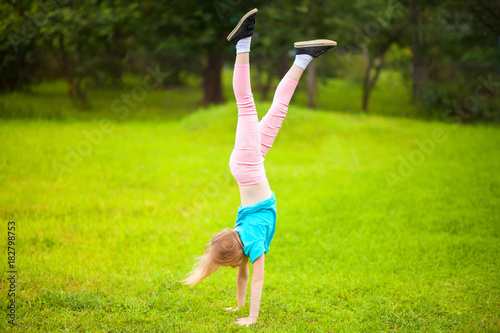 Photos Active little school girl somersault outdoors.
