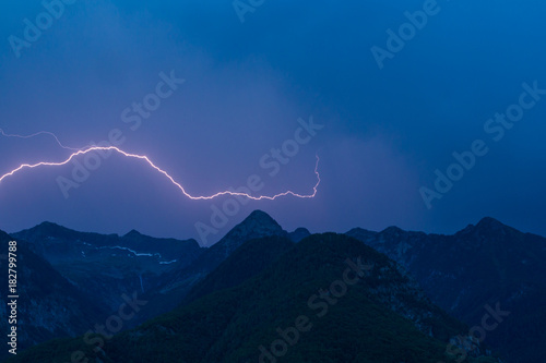 bolt lightning over mountain peak silhouette with dark blue sky