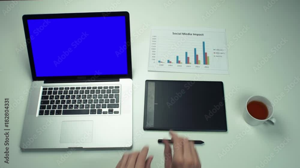 Top view male hands working with printed graphs using laptop with green screen Top view male hands working with printed graphs using laptop with green screen