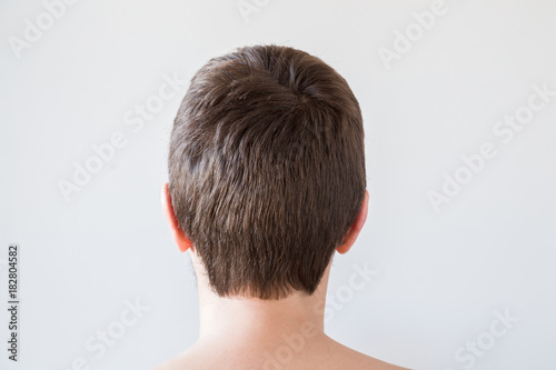 Man's brown hair after brushing with comb on the gray background. Cares about a healthy and clean hair. Beauty salon concept.