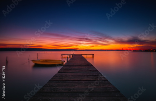 Fototapeta Naklejka Na Ścianę i Meble -  Wooden Dock and fishing boat at the lake, sunset shot