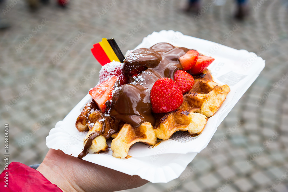Obraz premium Belgium waffle with chocolate sauce and strawberries, Bruges city background
