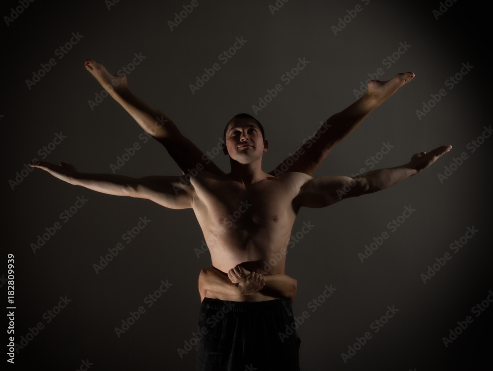 Young sports couple doing acroyoga exercises in a dark room