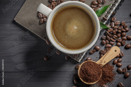 Hot coffee cup with coffee beans and the ground powder of coffee on the wooden table