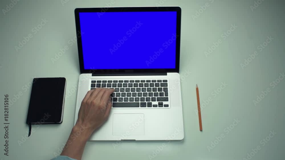 Top view male hands using laptop computer with green screen at white desk Top view male hands using laptop computer with green screen at white desk