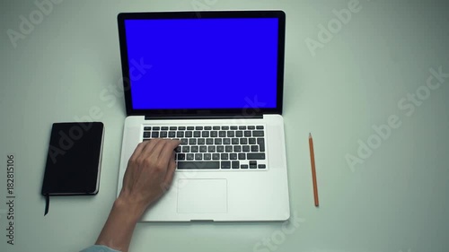 Top view male hands using laptop computer with green screen at white desk