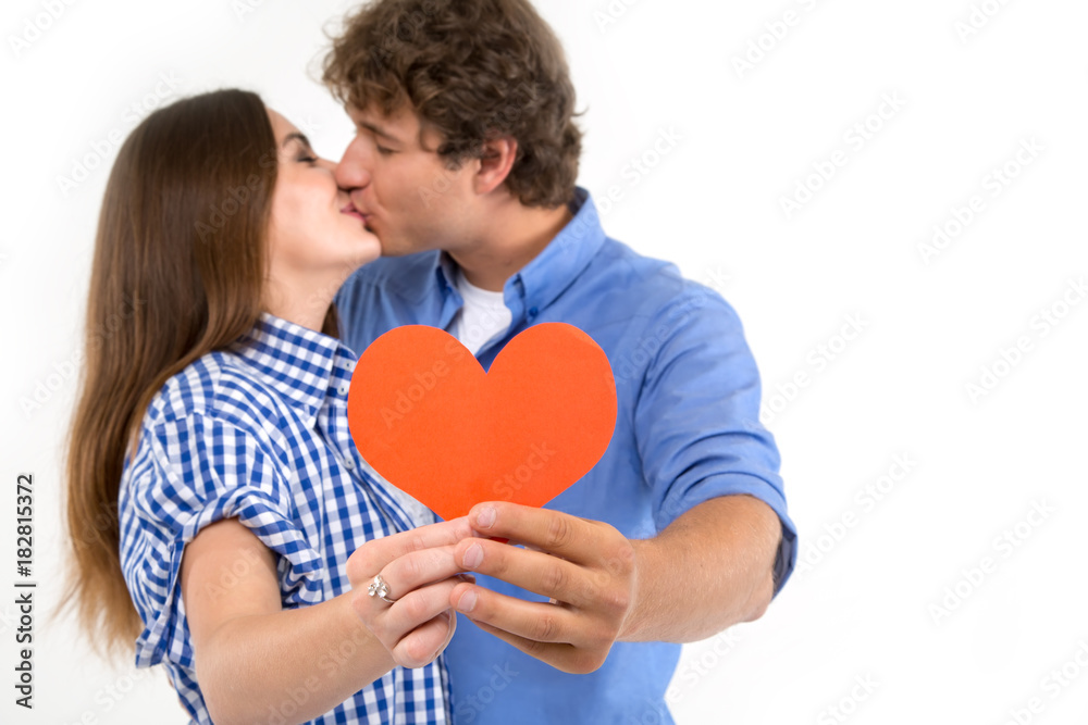 Happy loving couple. Kissing couple. Enamored couple of young people. Man and woman holding in their hands red hearts. Symbol of love. Valentine's Day.