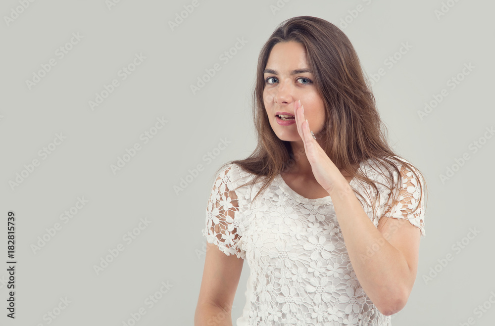 Young woman holding hand near mouth and telling secret. Young woman holding hand near mouth and telling secret.