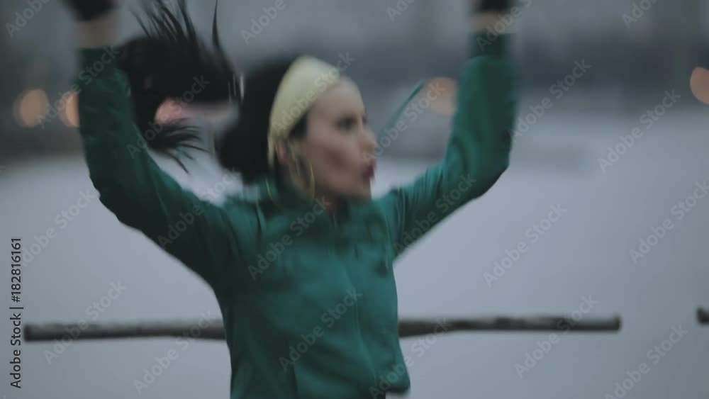 Sportswoman jumping and warming up in cold winter city