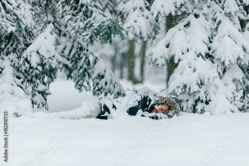 Man in snow. Homeless male sleeping outdoor under trees. Odd bizarre shocked traveler guy freezing on ground in frost winter day. Unique person lifestyle. Overcoming challenges. Destination complete.