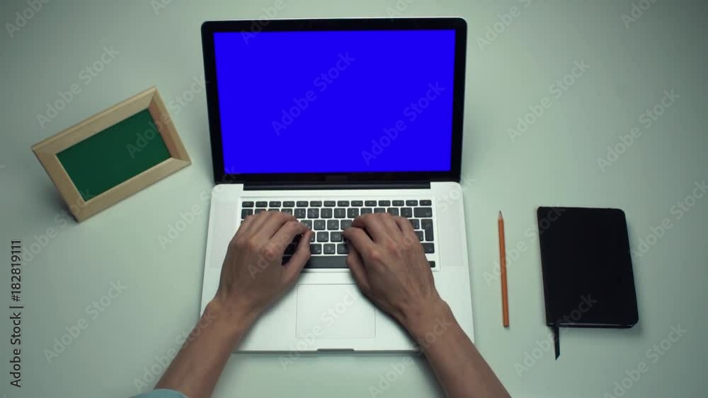 Office worker using laptop computer with green screen at white desk Office worker using laptop computer with green screen at white desk