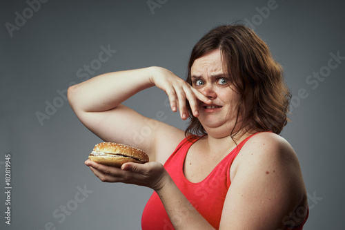 2043183 Harmful food, hamburger, hamburger stinks, woman with a hamburger, woman on a gray background