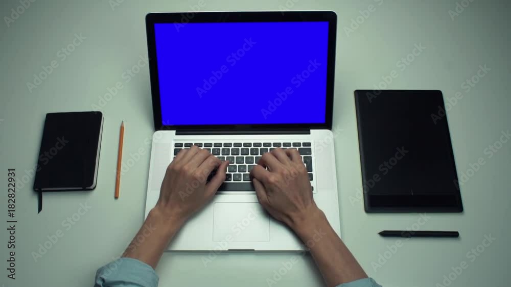Top view male hands using laptop computer with green screen at white desk. Top view male hands using laptop computer with green screen at white desk.