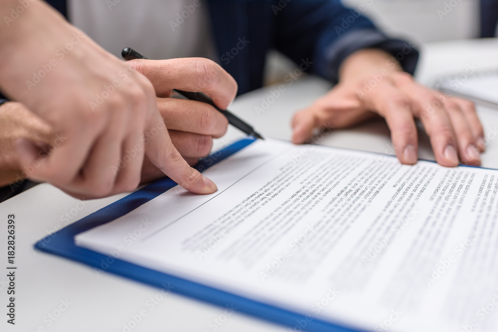 cropped shot of client signing contract while manageress pointing at it cropped shot of client signing contract while manageress pointing at it