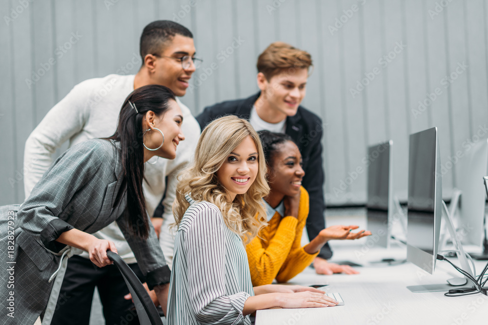 multiethnic managers looking at computer together in modern office multiethnic managers looking at computer together in modern office