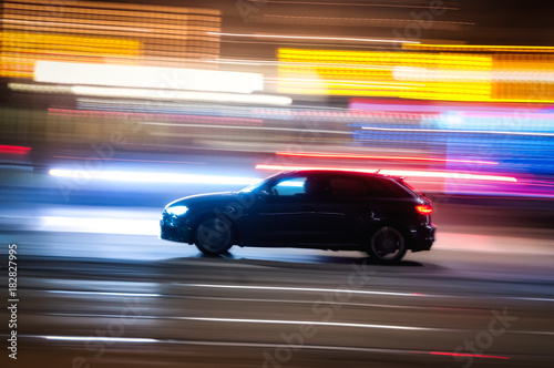 Automobile che sfreccia veloce di notte per le vie con luci colorate di una  grande città  photo