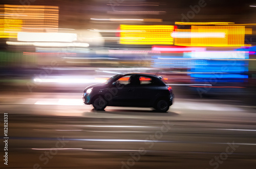 Automobile che sfreccia veloce di notte per le vie con luci colorate di una  grande città  © vpardi