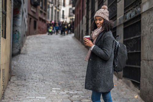 Young black woman drinking coffee wandering in the streets of Madrid on winter