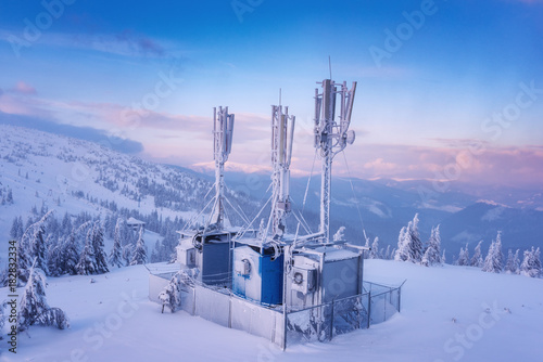 Cellular base station on the snowy winter mountain hill at sunset light