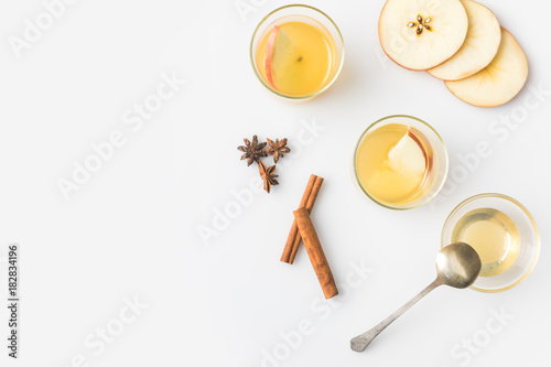top view of glasses of apple cider with spices isolated on white