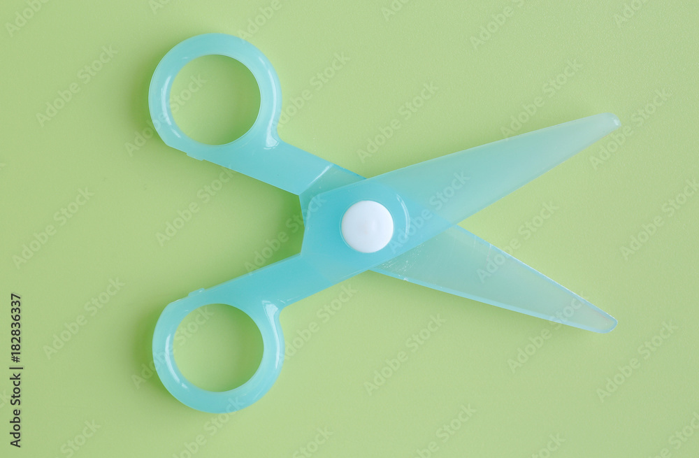 Cyan Plastic children safety scissors on green background. Cyan Plastic children safety scissors on green background.
