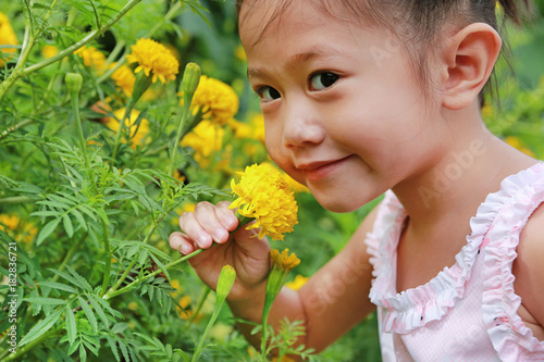 Asian little girl holding marigold flower in the hand.