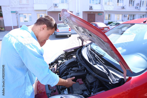Young man trying to repair damaged car