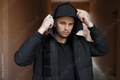 Canvas Print Stylish fashionable young man in a trendy black baseball cap in a winter fashion