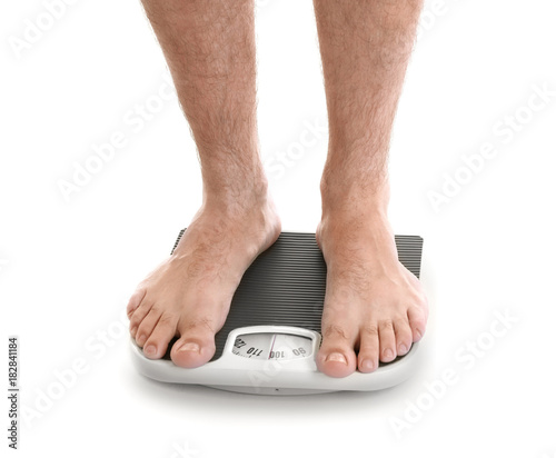 Overweight man measuring his weight using scales on white background