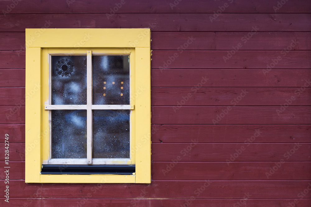 Christmas fair cabin's window with snow pattern on brown wooden wall with copy space. Light yellow window with brown plank background Christmas fair cabin's window with snow pattern on brown wooden wall with copy space. Light yellow window with brown plank background