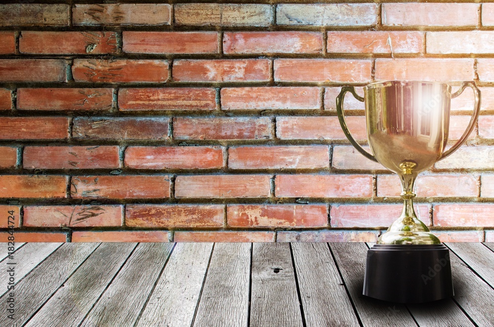 champion golden trophy on wooden desk and lens flare effect with old  vintage brick wall background, winner, success and congratulation concept,  copy space for display of product presentation Photos | Adobe Stock