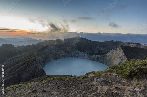 Fog drifts past Danau Kootainuamuri crater as the sun rises in the distance at Kelimutu National Park in Indonesia.
