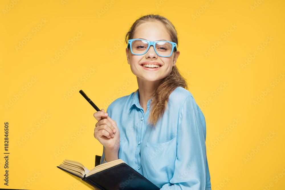 Young beautiful woman on a yellow background with glasses points to an empty space Young beautiful woman on a yellow background with glasses points to an empty space