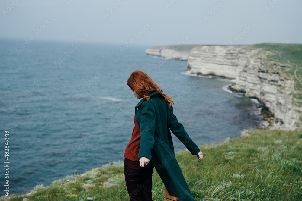 Young beautiful woman on a cliff near the sea, nature