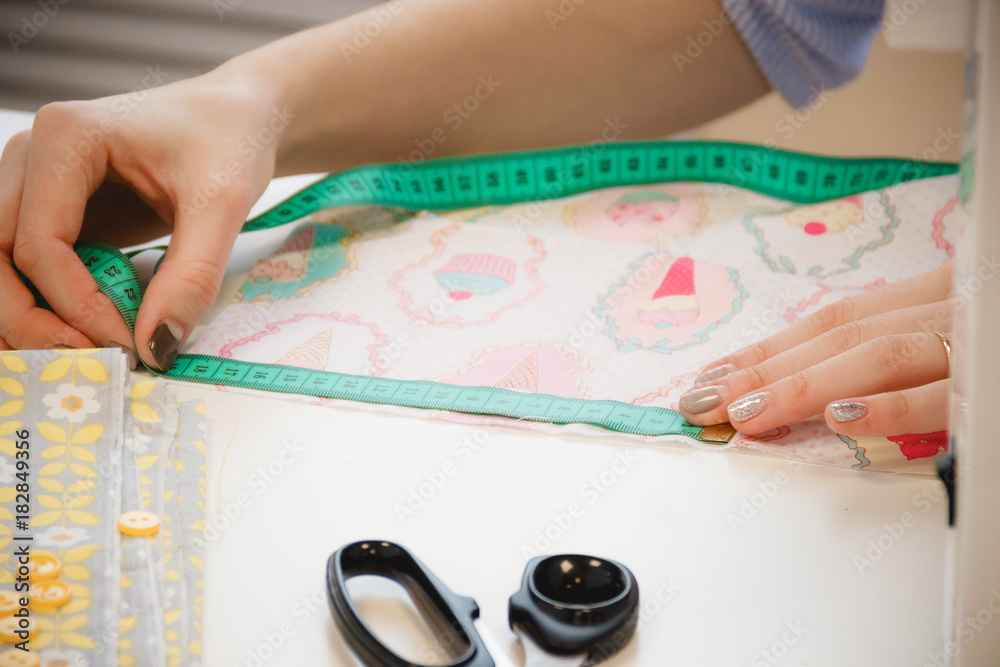 Seamstress hands on the work table with pattern and measuring tape Seamstress hands on the work table with pattern and measuring tape