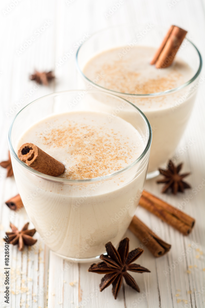 Homemade eggnog with grated nutmeg and cinnamon on white wooden table. Traditional Christmas drink. Homemade eggnog with grated nutmeg and cinnamon on white wooden table. Traditional Christmas drink.