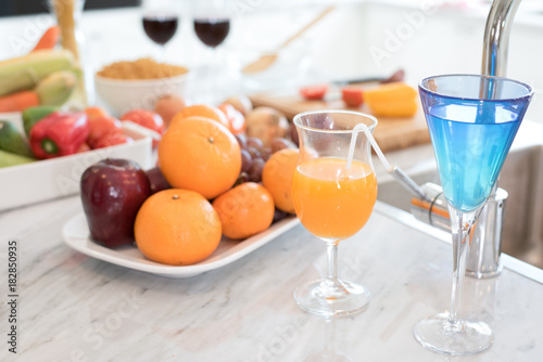 Fruit and fruit juice on marble counter in kitchen room. Apple and orange juice and vegetable on table. Food and drinks concept. Party and celebration theme