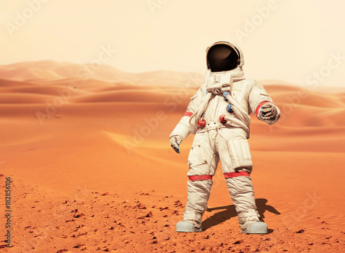 Man in a space suit standing on the red planet Mars. Spaceman conquer a new planet. Concept of the space