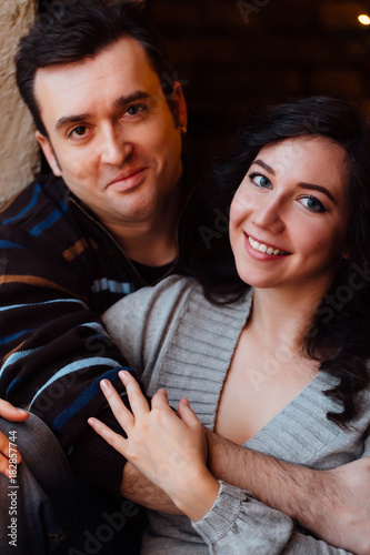 Couple of lovers hugs sitting on the windowsill in the Christmas loft studio. guy is hugging the girl.