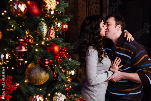Young couple in love decorates a Christmas tree at home