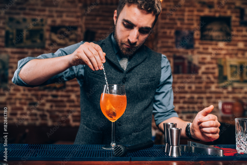 Portrait of professional bartender preparing cocktail, refreshing alcoholic drink in nightclub