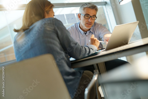 Colleagues working together in office, using laptop