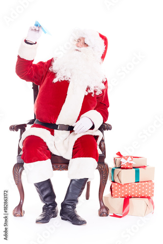 Portrait of Santa Claus sitting in chair and launching paper airplane