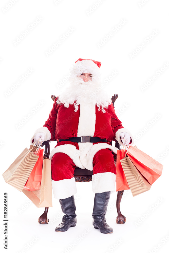 Santa sitting in chair and holding bunches of bags after Christmas shopping