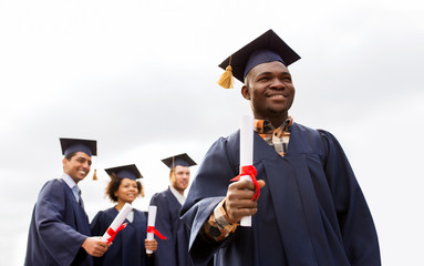 happy students in mortar boards with diplomas