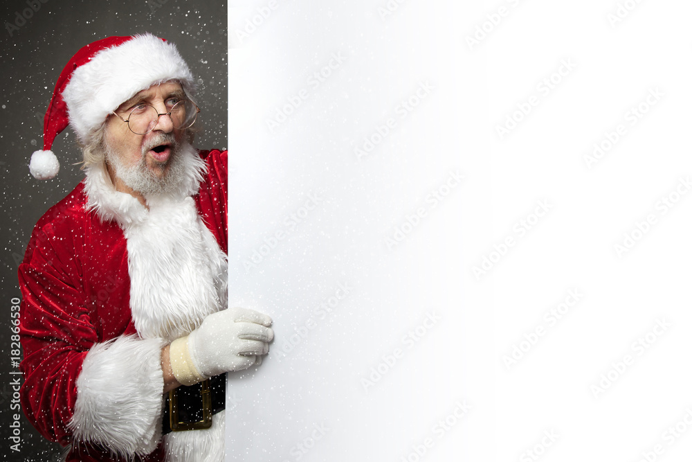 Santa Claus showing something on a white wall