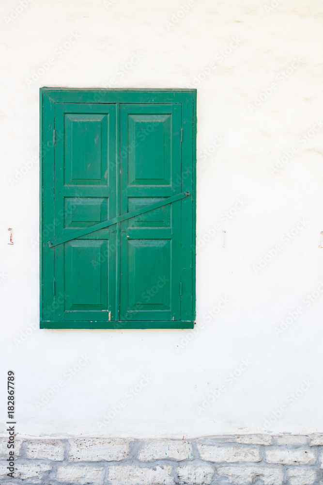 One green windows on a white wall