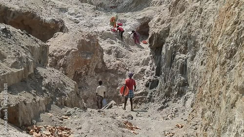 Employment and manual labor in India, poor unrecognisable men Indian mine worker comes with empty basins. Mining minerals in third world countries.