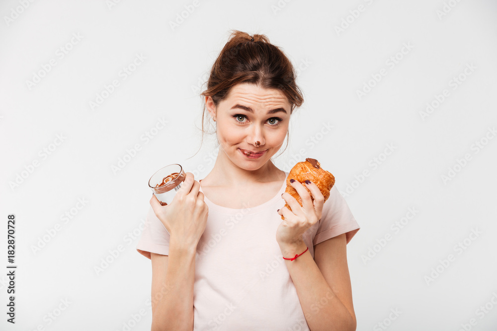 Portrait of a smiling pretty girl eating croissant